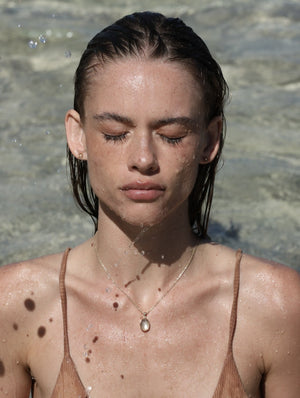 green moonstone necklace on model in clear tropical water with water dripping from chin