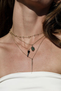 layered 14k gold necklaces with shark tooh and seaglass pendants on model