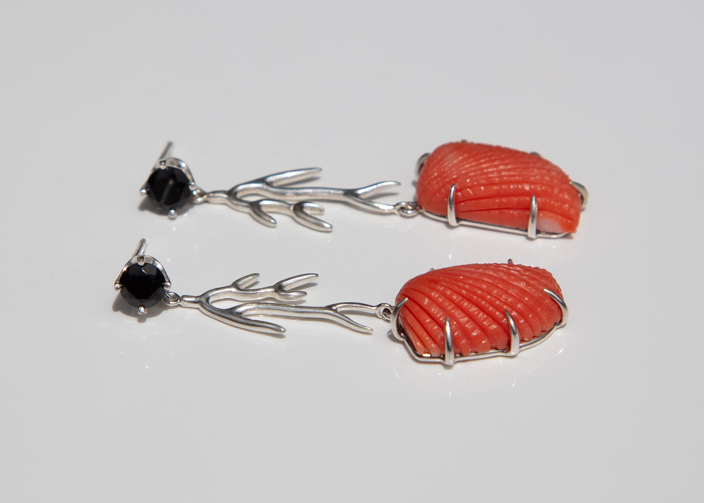 Coral and black stone earrings on a light gray background