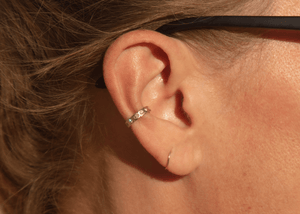 14k gold ear cuff with diamonds and notched details on model in sunlight