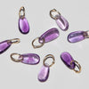 14k gold teardrop shaped amethyst charms on a light background