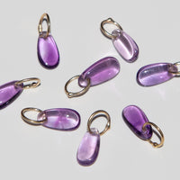 14k gold teardrop shaped amethyst charms on a light background