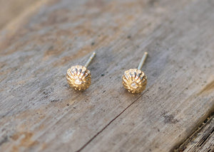 tiny gold seed earrings with diamonds in center on wood