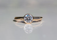 gold wave engagement ring with diamond on gray background