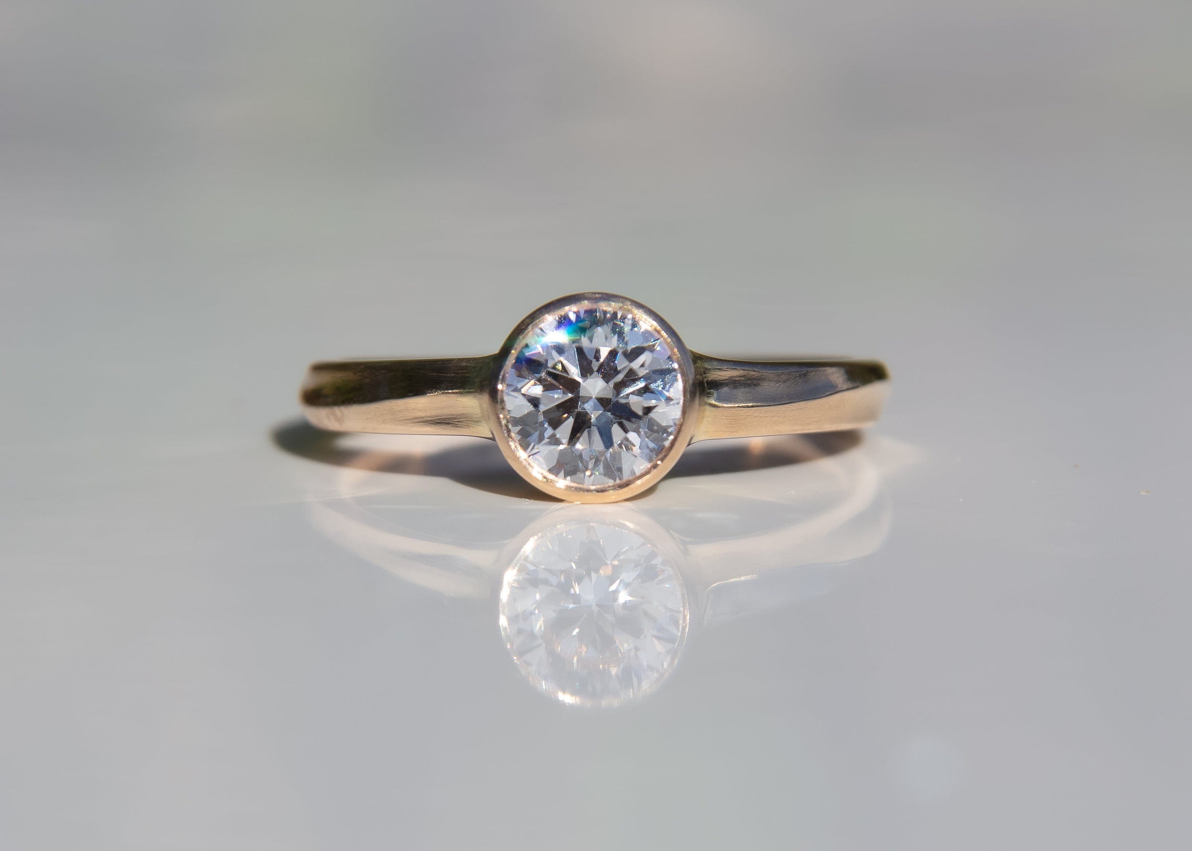 gold wave engagement ring with diamond on gray background