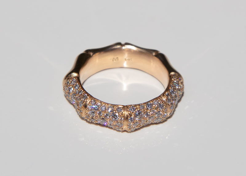 Gold bamboo ring with pave set diamonds on a light gray background