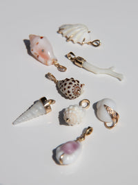 Seven seashell-shaped jewelry charms with gold-tone hardware, displayed on a clean white background.