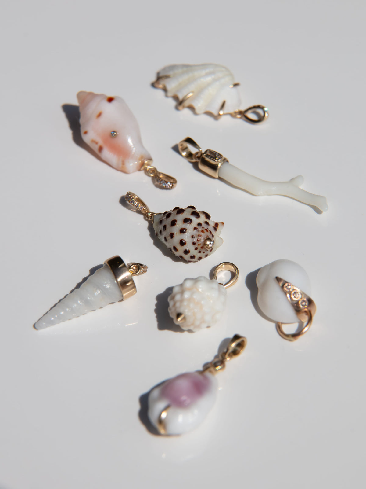 Seven seashell-shaped jewelry charms with gold-tone hardware, displayed on a clean white background.
