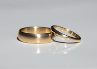 hammered gold wedding band set on a reflective surface with a light gray background