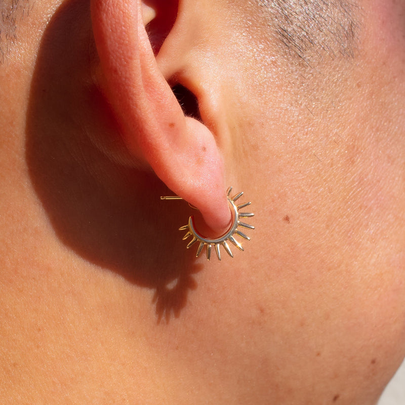 small spiky gold earrings on ear