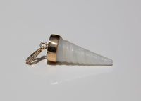A spiral cone-shaped shell pendant with a polished gold cap and a small gold diamond-studded bail at the top, shown on a reflective light gray surface.