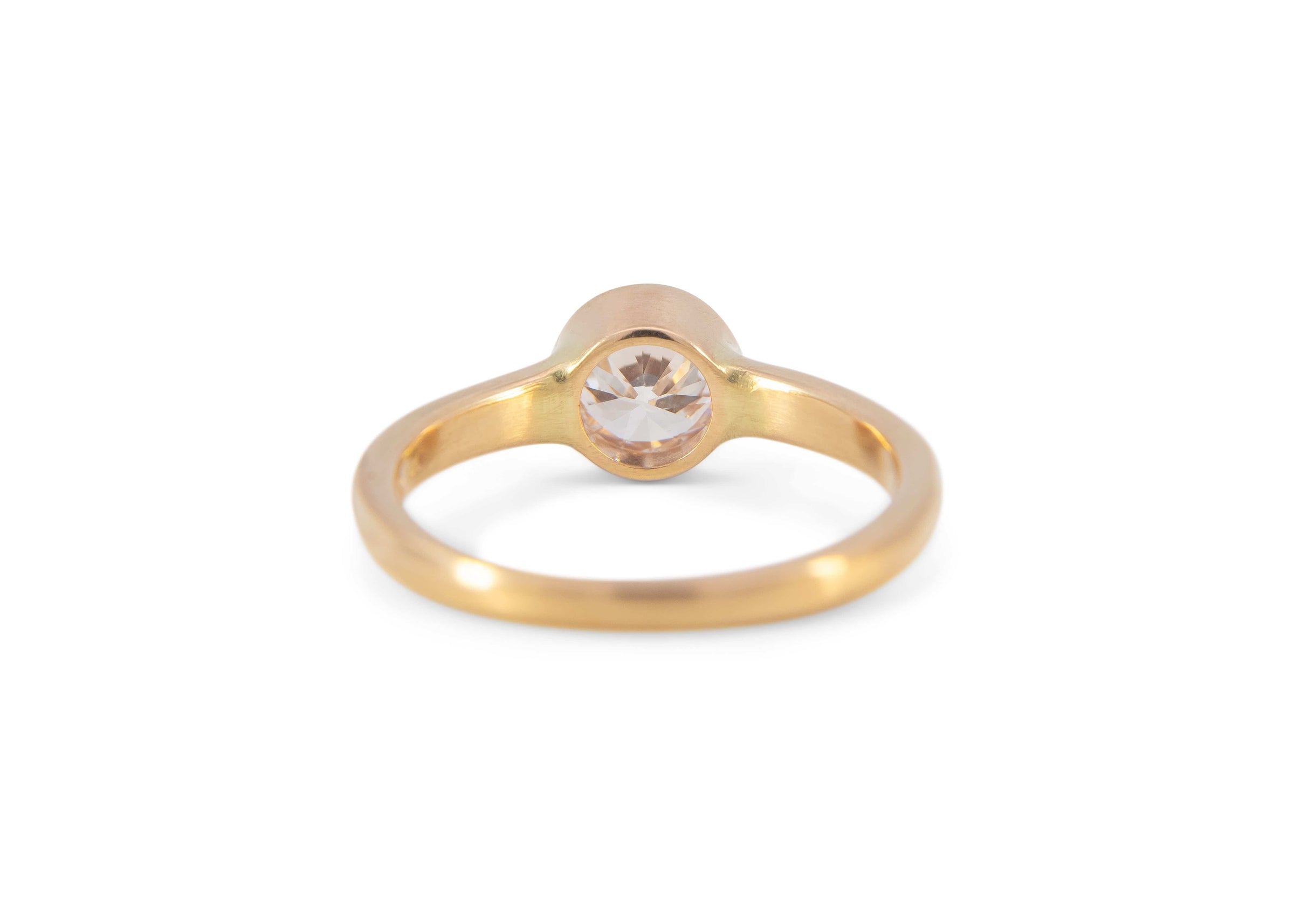 back of gold ring with a diamond on a white background