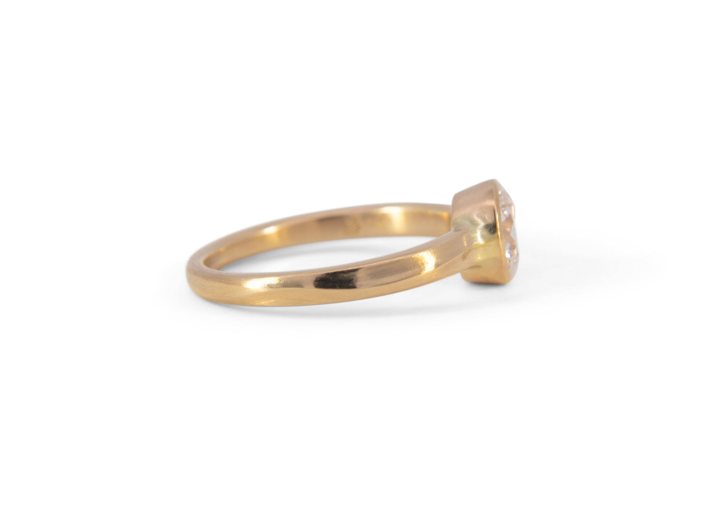 side view of gold wave engagement ring with diamond on white background