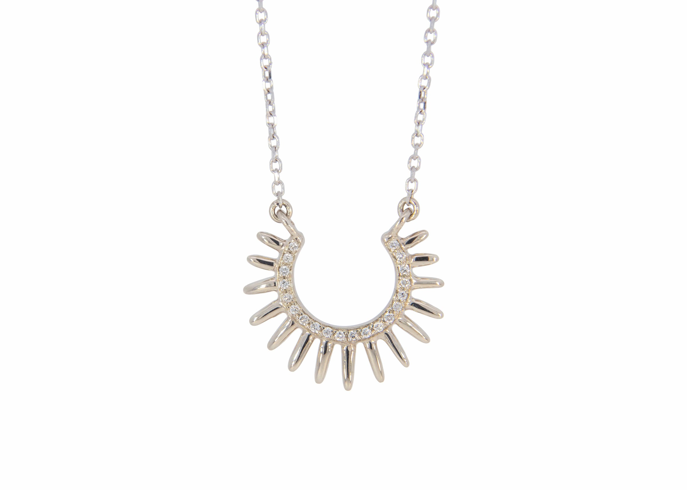 Silver sun-shaped necklace with small stones on a white background