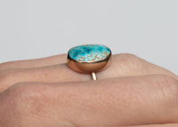 side view of 14k gold bezel set iron maiden turquoise ring on hand