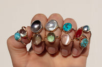 assorted gemstone and mabe pearl rings on hand