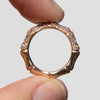 Gold bamboo ring with pave set diamonds held between fingers against a neutral background