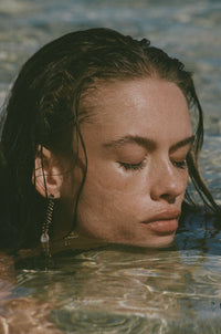 tiny geode earrings on model in clear water