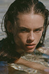 tiny geode earrings on model in clear water