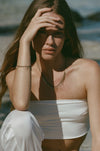 fringe style bracelet and necklace with gold spikes on model wearing white clothing