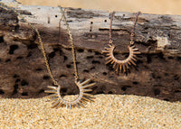 gold urchin necklaces with diamonds on driftwood and sand