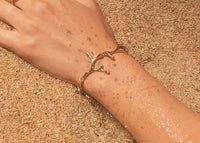 14k gold limu seaweed bracelet on wrist in sand