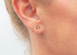 small gold flower post earrings with diamond studs on ear