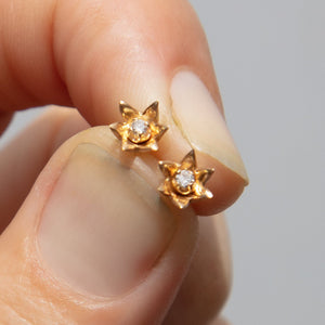 small gold flower post earrings with diamond studs in hand