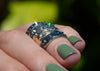 urchin shell inspired rings with inverted gemstones on hand with green nail polish