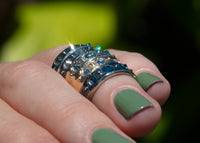 urchin shell inspired rings with inverted gemstones on hand with green nail polish